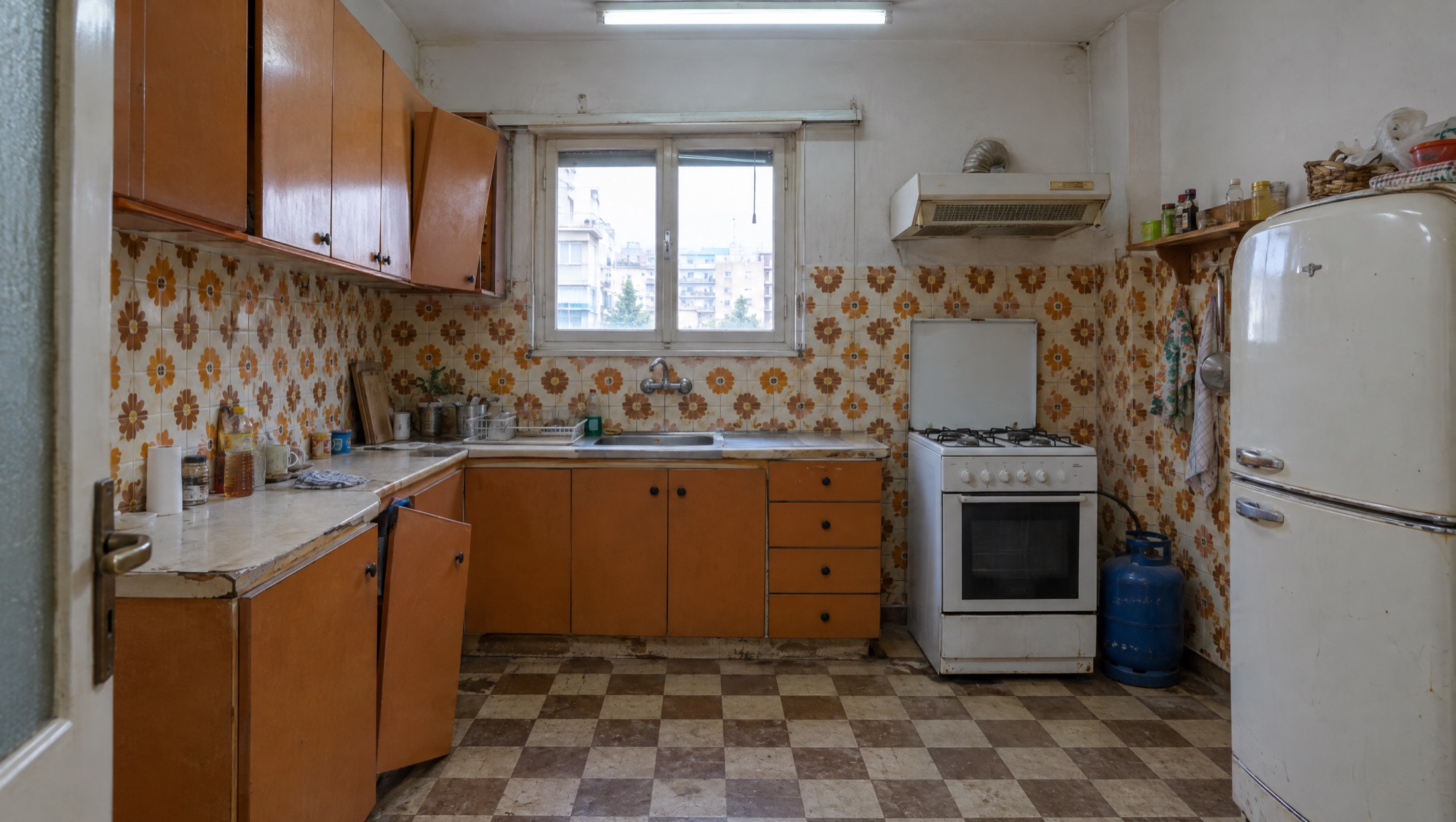 Η ίδια κουζίνα πριν, με ντουλάπια φορμάικας, λουλουδάτα πλακάκια και κουζίνα υγραερίου